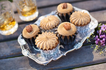 Salted Caramel Bourbon Cupcakes in Black Cupcake Wrappers Topped with Pecan Halves on Silver Tray...
