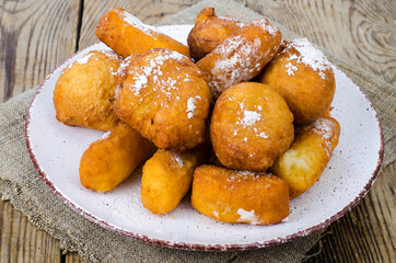 Sweet curd donuts buns with powdered sugar on wooden table