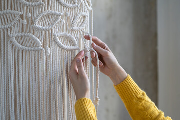 Close up of freelancer woman working on half-finished macrame piece, weaves lamp shade for chandelier. Women hobby. - obrazy, fototapety, plakaty