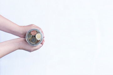 October 31 - World Savings Day - hands holding a glass jar with coins. White background. conceptual.