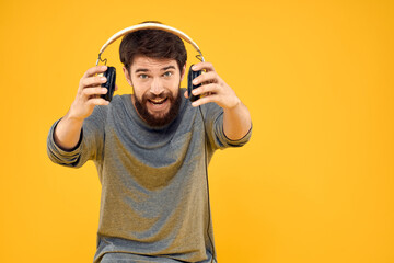 Fototapeta premium Man in headphones listens to music technology lifestyle fun people yellow background