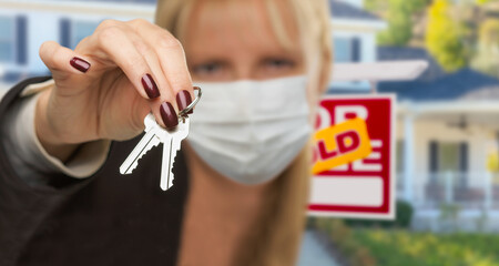 Woman Presenting House Keys Wearing Medical Face Mask