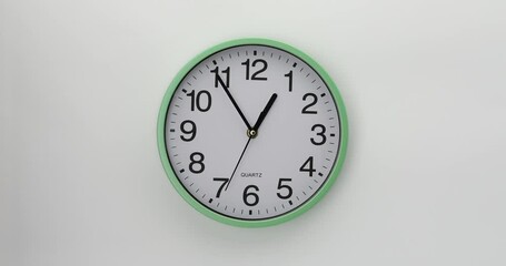 Quartz wall clock on a white background. The clock shows five minutes to one. 4K DCI video. 