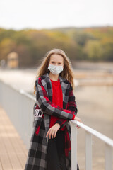 Cute girl teen in a mask on a walk in the fall