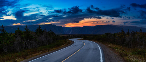 Scenic curvy road in the Canadian Landscape. Dramatic Colorful Sunset Artistic Render. Taken in Gros Morne National Park, Newfoundland, Canada.