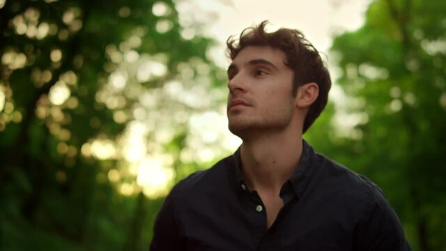 Relaxed man spending time outdoors. Sensual guy enjoying walk on road in park