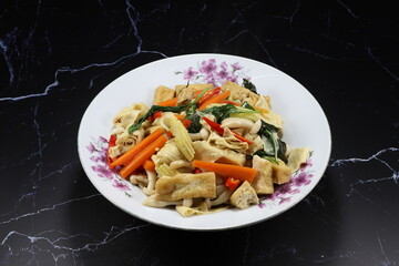 Fried and stirred spicy dried tofu with carrot, basil and chilly on the plate. Famous vegetarian menu in Chinese restaurant. High fiber and low fat menu.