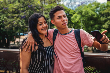 Naklejka premium Young Couple of Smiling Students Making Selfie Outdoors.