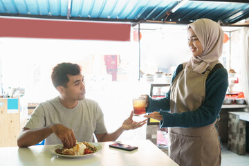 a woman gives a drink to a man who is eating