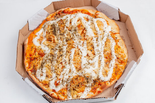 Round chicken pizza with catupiry cheese on a white table.