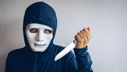 An unidentified man with mask holding a sharp knife waiting for his victim. Conceptual of a person who commits a crime.