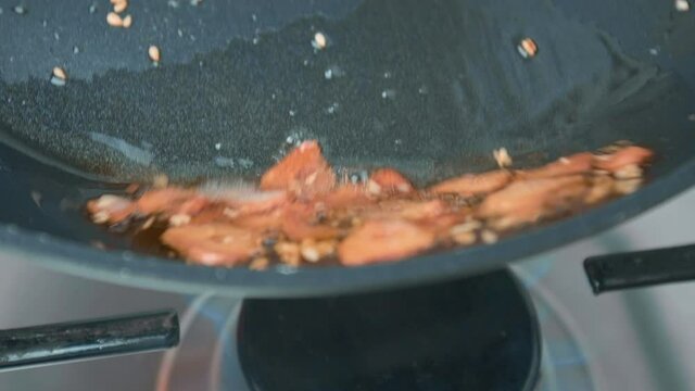 Frying sliced garlic into a pan until golden crisp, making garlic chips in 4K.