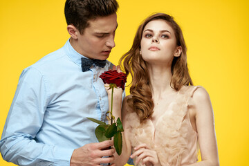 Enamored man and woman with red rose on yellow background cropped view close-up romance