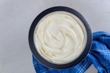 Homemade vanilla whipped cream in a bowl with blue towel.
