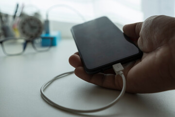 Close-up Smartphone battery charge Inside the house on the desk in warm light