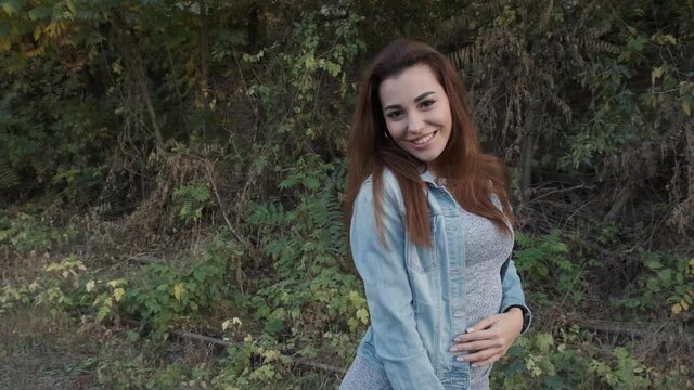 Beautiful girl in a dress with a denim jacket on the railroad tracks. Smiling, spinning. Slow motion. Shot in 4k