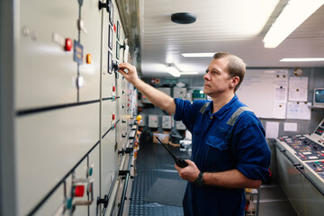 Marine engineer officer controlling vessel engines and propulsion in engine control room ECR. Ship maintenance Start or stop of main engine