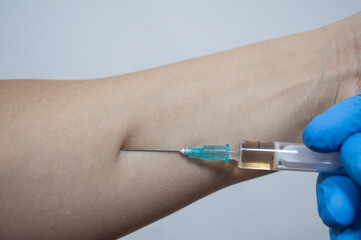Hand in gloves makes an injection in the arm,  injection, vaccination