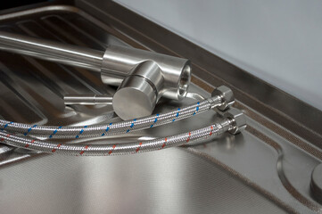 Installation of the kitchen faucet to a sink. A kitchen faucet is fitted with hoses for installation