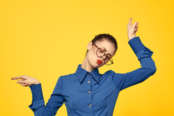 woman with glasses and blue shirt gesturing with her hands on yellow background cropped view Copy Space