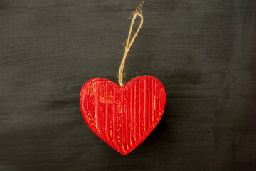 Red vintage wooden heart on black background.