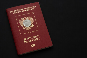 Russian foreign passport with ruble coin on black background. Copy space