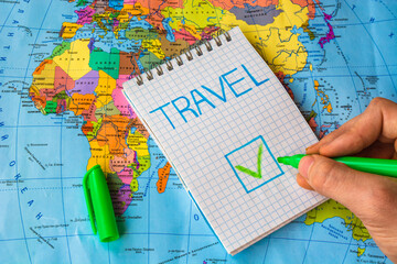 Check green mark in check box "Travel" against colorful world map background. Post pandemic travellings concept