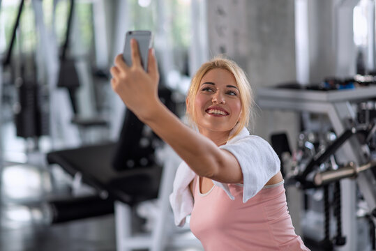 Young sportive woman taking selfie with mobile phone in gym