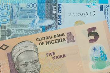 A macro image of a orange, plastic five naira note from Nigeria paired up with a blue, plastic five hunded tenge bank note from Kazakstan.  Shot close up in macro.