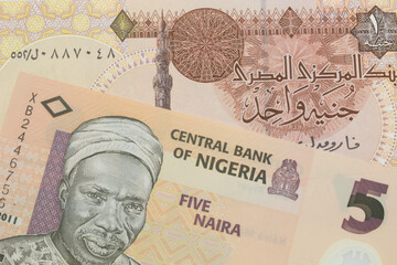A macro image of a orange, plastic five naira note from Nigeria paired up with a one pound banknote from Egypt.  Shot close up in macro.