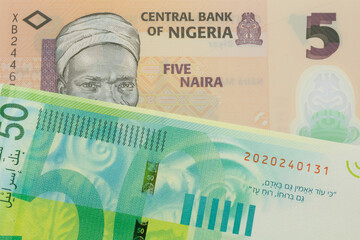 Fototapeta premium A macro image of a orange, plastic five naira note from Nigeria paired up with a green and white fifty shekel bank note from Israel. Shot close up in macro.