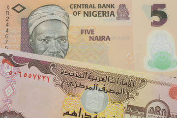 A macro image of a orange, plastic five naira note from Nigeria paired up with a colorful five dinar bank note from the United Arab Emirates.  Shot close up in macro.