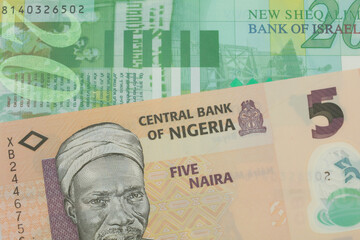 A macro image of a orange, plastic five naira note from Nigeria paired up with a green and white fifty shekel bank note from Israel.  Shot close up in macro.