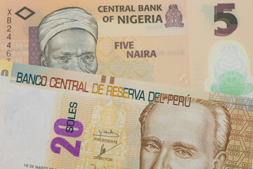 A macro image of a orange, plastic five naira note from Nigeria paired up with a beige, twenty sol bill from Peru.  Shot close up in macro.