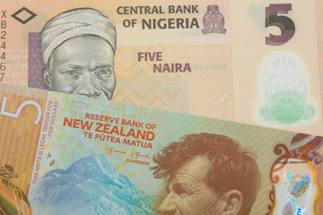 A macro image of a orange, plastic five naira note from Nigeria paired up with a orange, plastic five dollar bill from New Zealand.  Shot close up in macro.