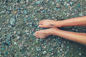 Legs of a young woman on a stone beach