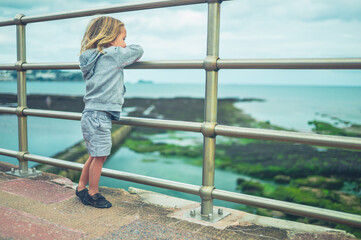 Preschooler playing by railing on the beach in autumn