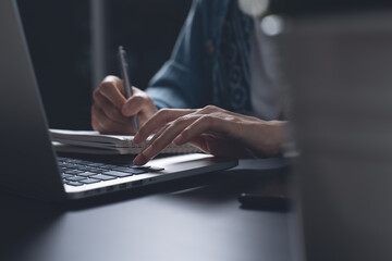 Female student studying online course via laptop computer  and writing on notebook at home