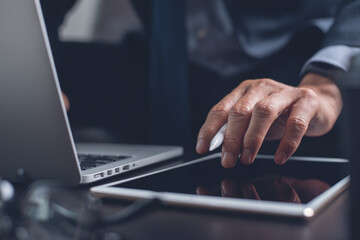 Businessman hand using on digital tablet touching on screen and working on laptop computer in office