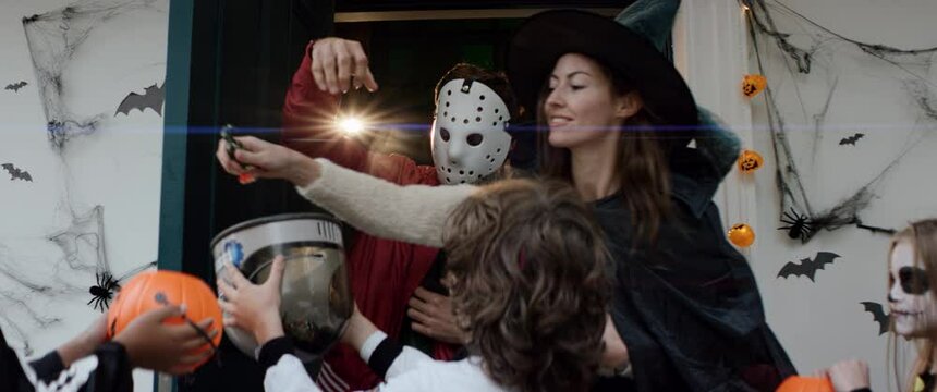 Hosts giving candies to a group of trick-or-treating kids during Halloween. Shot on RED Cinema camera with 2x Anamorphic lens