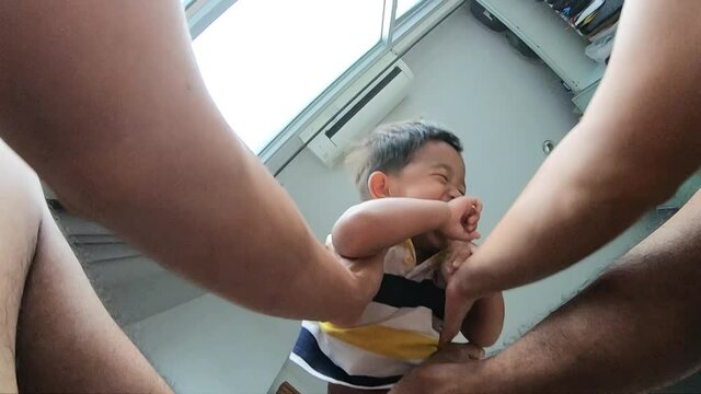 Father hand lifting funny boy up and down in cozy room family concept
