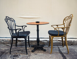 A table with 2 chairs next to a wall. Street cafe in the center of Bucharest city.