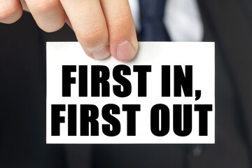 Businessman shows a card with the text FIRST IN, FIRST OUT