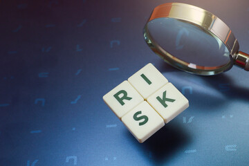 Close view of block letters on risk with a magnifying glass on the laptop cover 