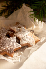 Star-shaped gingerbread cookies sprinkled with powdered sugar lying under a christmas tree