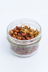 Fried Asian Anchovies "ikan bilis" with Fried peanuts in a transparent glass jar isolated on white background. Center of the frame