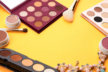 Professional eyeshadows and makeup brushes on a yellow background make-up decoration