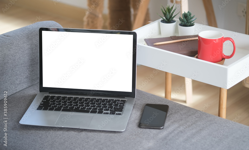Aufkleber close up view of an open laptop computer with blank screen and a mobile phone are putting on sofa in