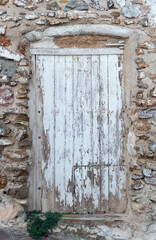 PRECIOUS OLD COVERED WHITE DOOR ON ANCIENT STONE WALL