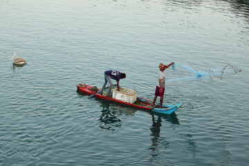Fototapeta premium The fisherman rode a boat made of wood and threw the net in the morning to catch the fish from the lake.